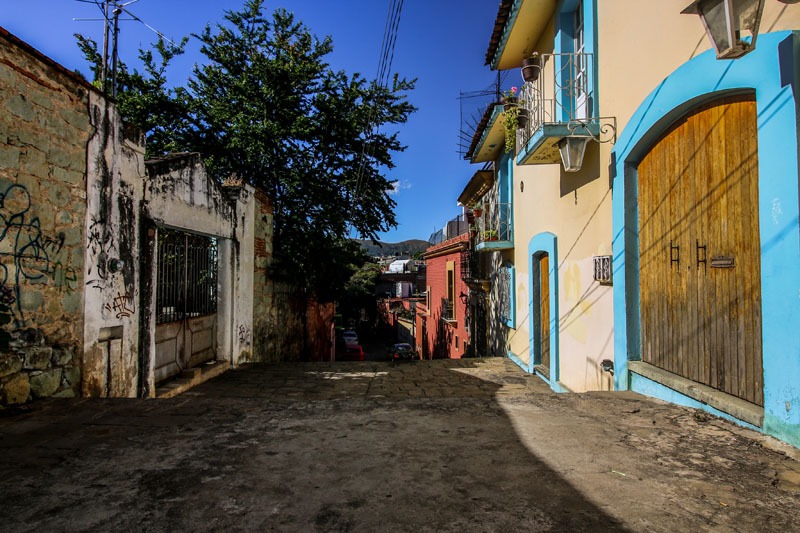 An alleyway with colourful buildings on the right, and a crumbling wall on the left