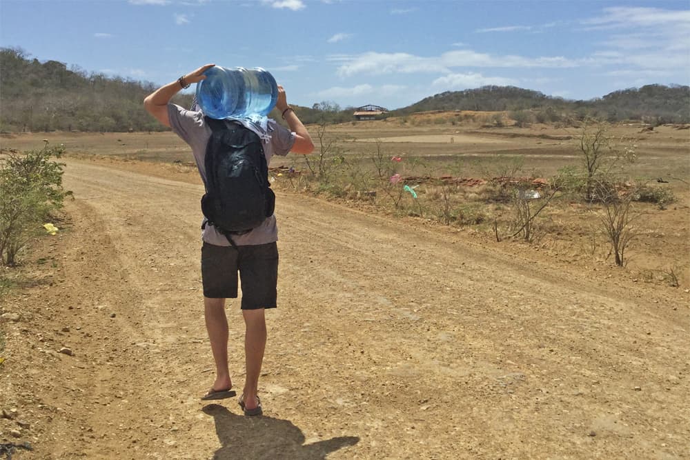 Nicaragua Accommodation Mark walking down a dusty road with a water bottle on his shoulder