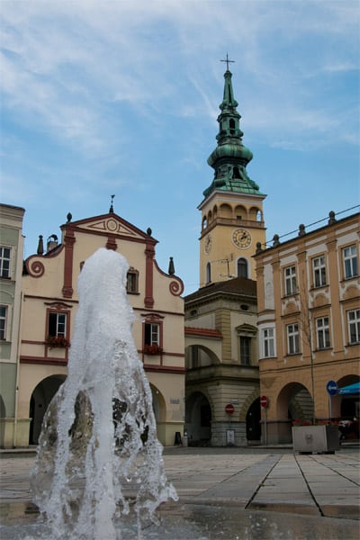 A fountain in a town square, old buildings surrounding it