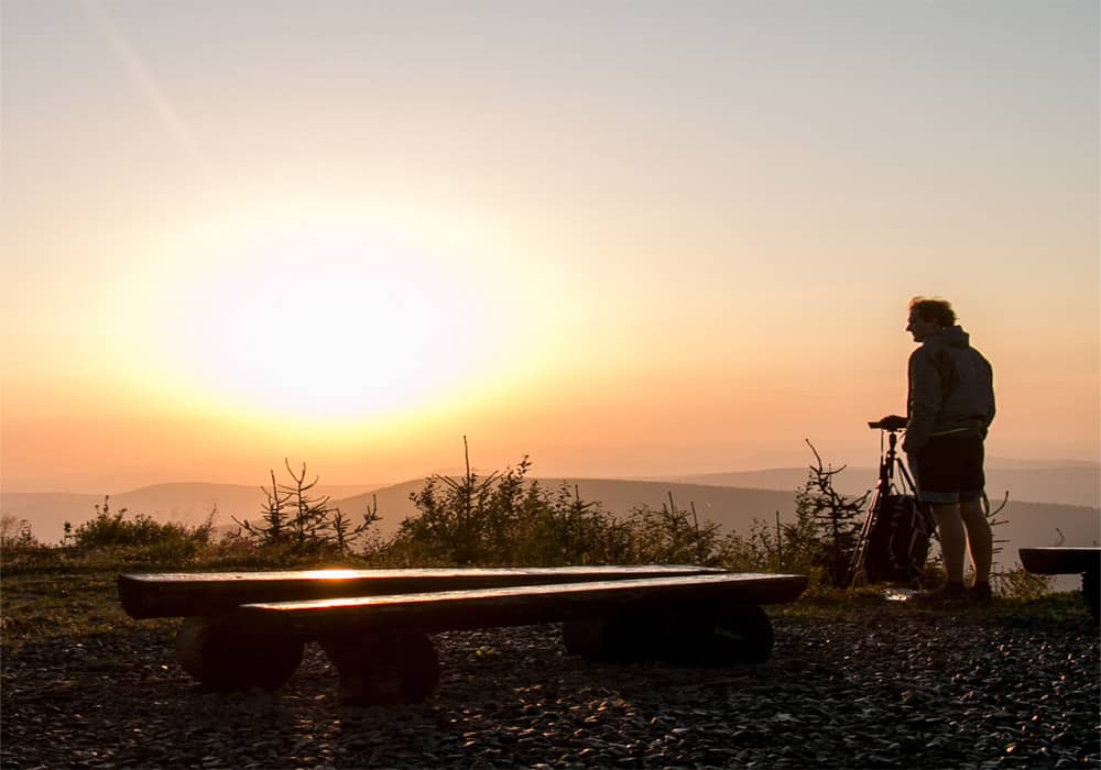 A photographer stands looking at the sunrise from Lysa Hora