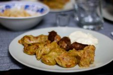 Plate of cabbage rolls with sausage and sour cream.
