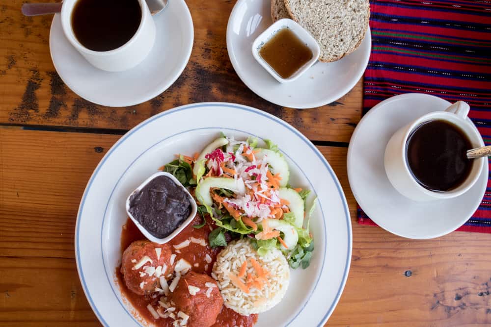 Plate of food including rice, beans, salad and meatballs with two coffees from Alma de Colores restauant San Juan Lake Atitlan