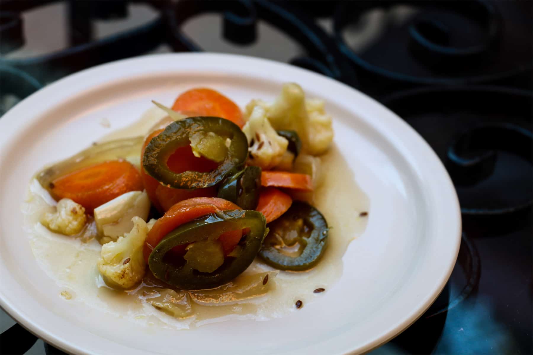 White plate with pickled jalapenos and vegetables