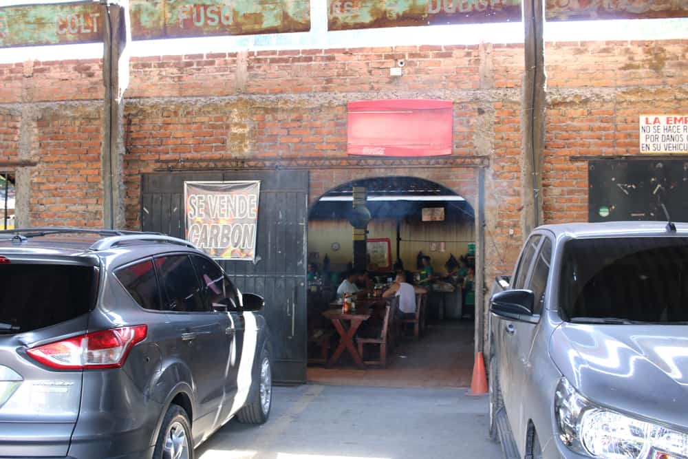 Doorway in a brick wall between two parked cars.