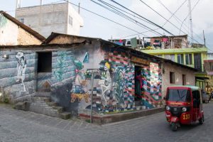 Small red moto taxi beside graffiti wall