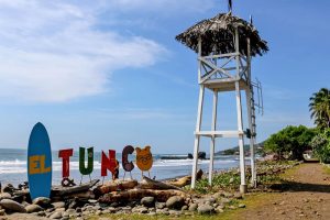 Sign that says "El Tunco" beside a wooden tower