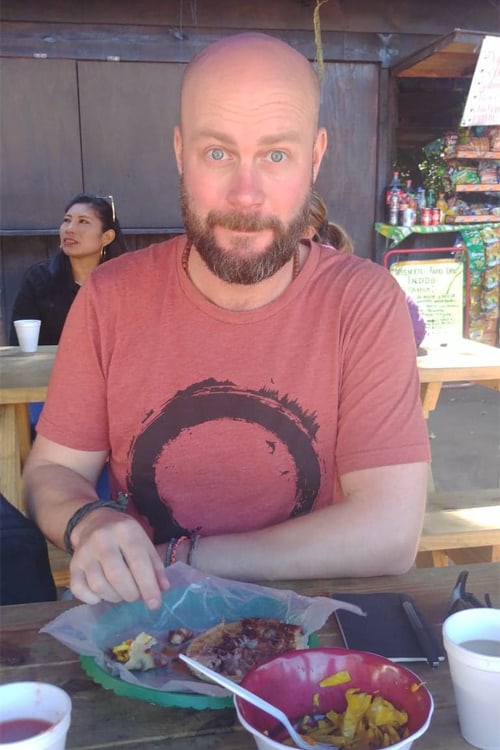 Man in red shirt with a plate of food in front of him in El Salvador