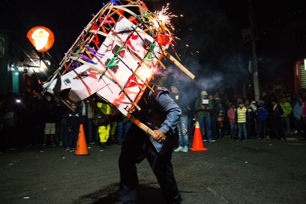 Man holding wooden bull costume shooting fireworks on the street