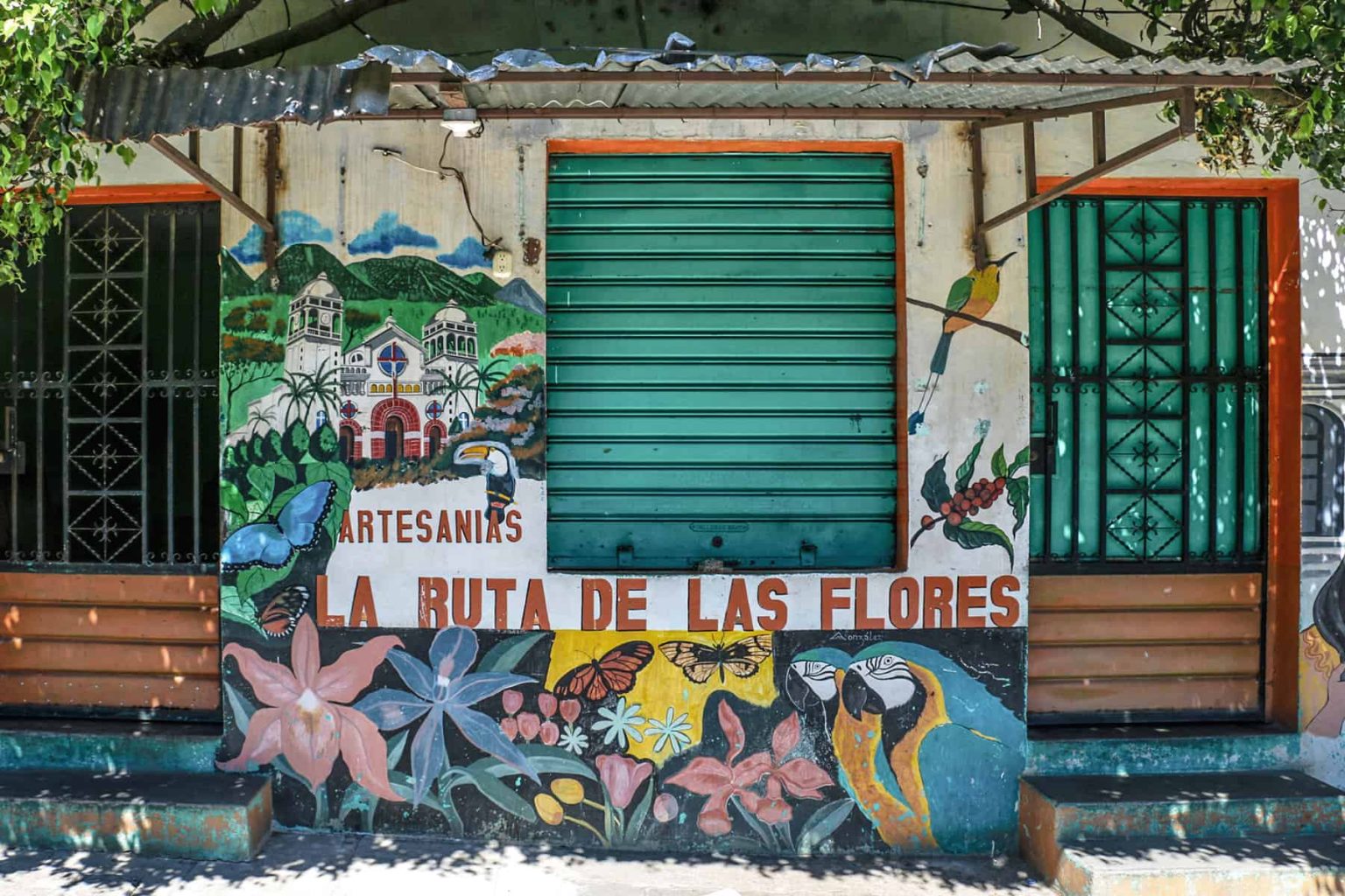 Colourful building front with green shutters and graffiti flowers in the Ruta de Flores