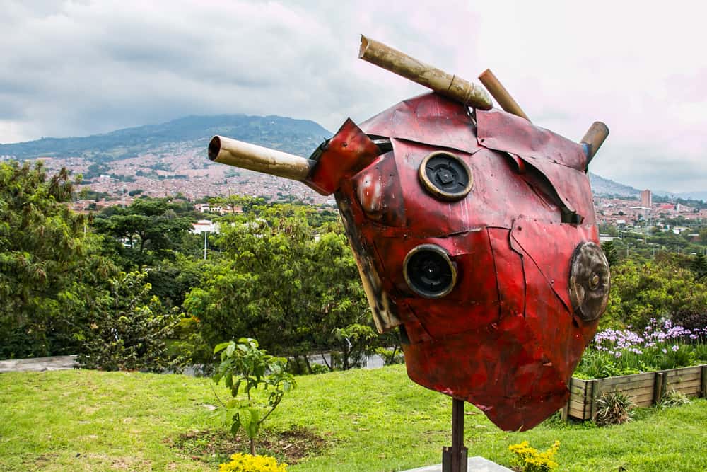 Red heart sculpture with a green hill in the background