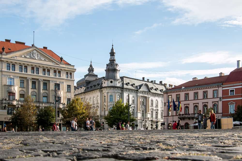 Union Square in Cluj. Cobblestones surrounded by colourful buildings.