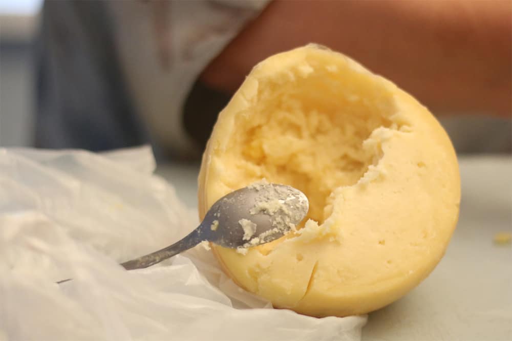 A ball of cheese with a spoon sticking out