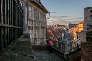 Sibiu Romania: Girl standing near a rooftop at sunset