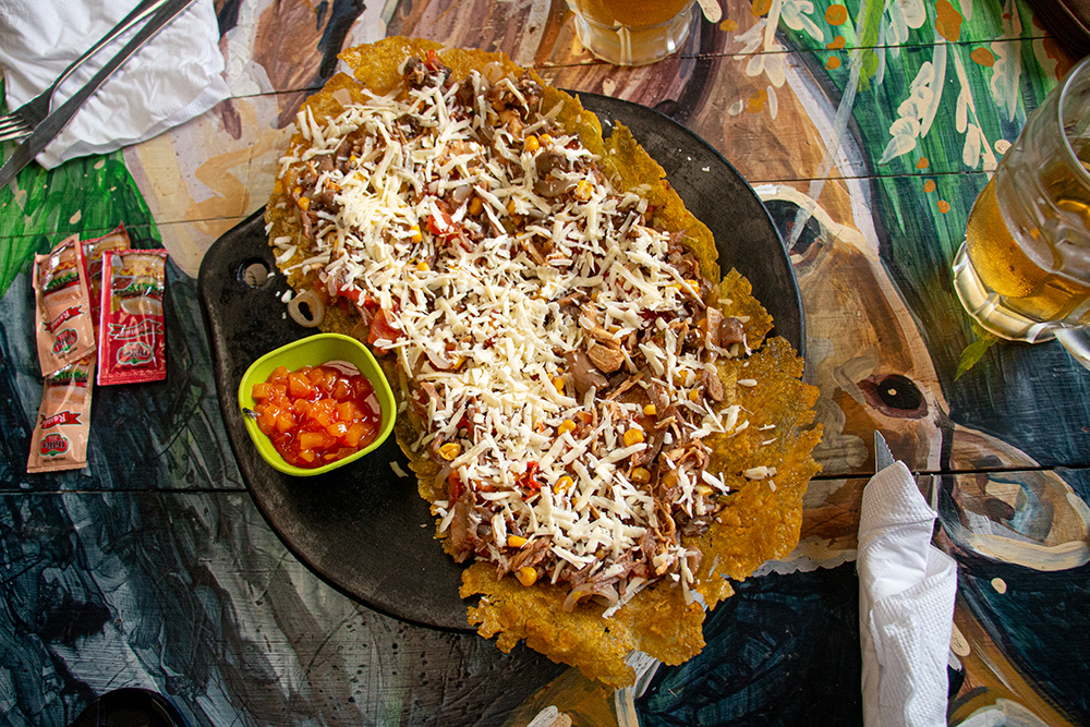 Large flat piece of fried plantain covered in cheese.