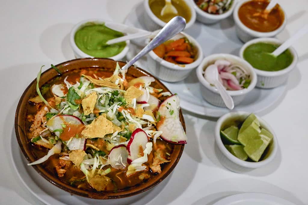 A soup in Oaxaca with a plate full of condiments