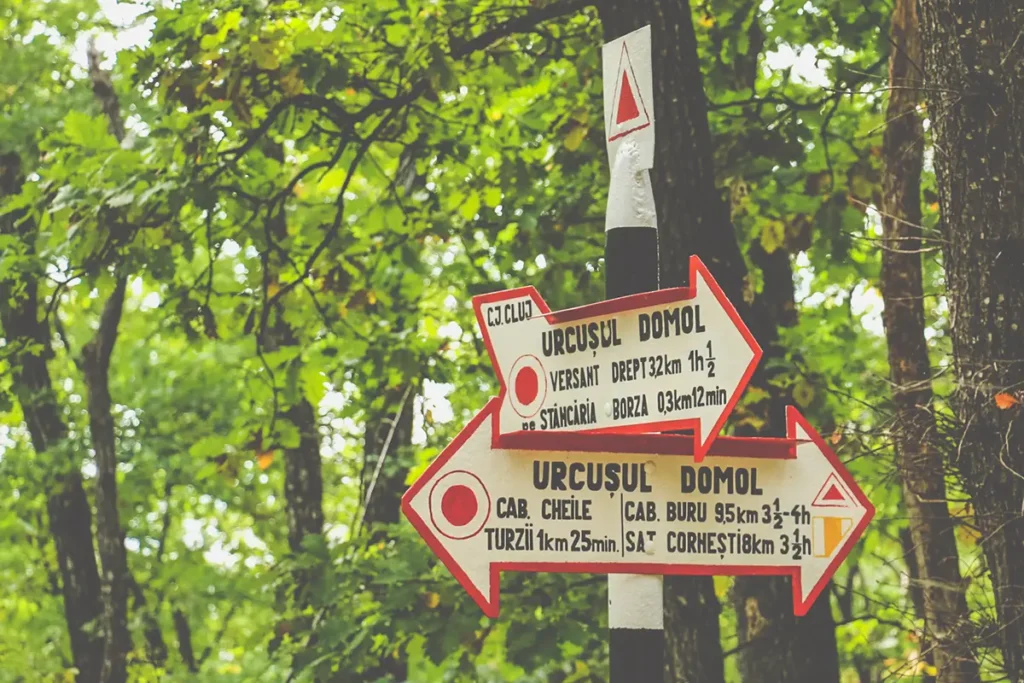 Sign post listing different hiking routes through Turda Gorge.