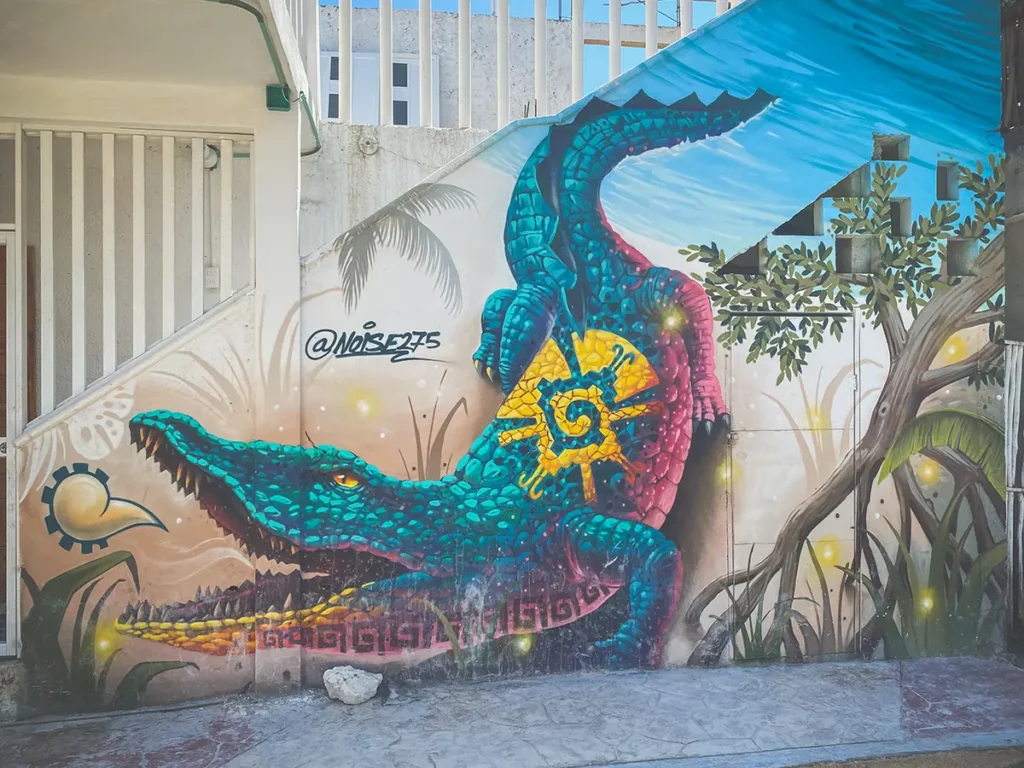 Graffiti of a crocodile painted bright blue, pink and yellow.