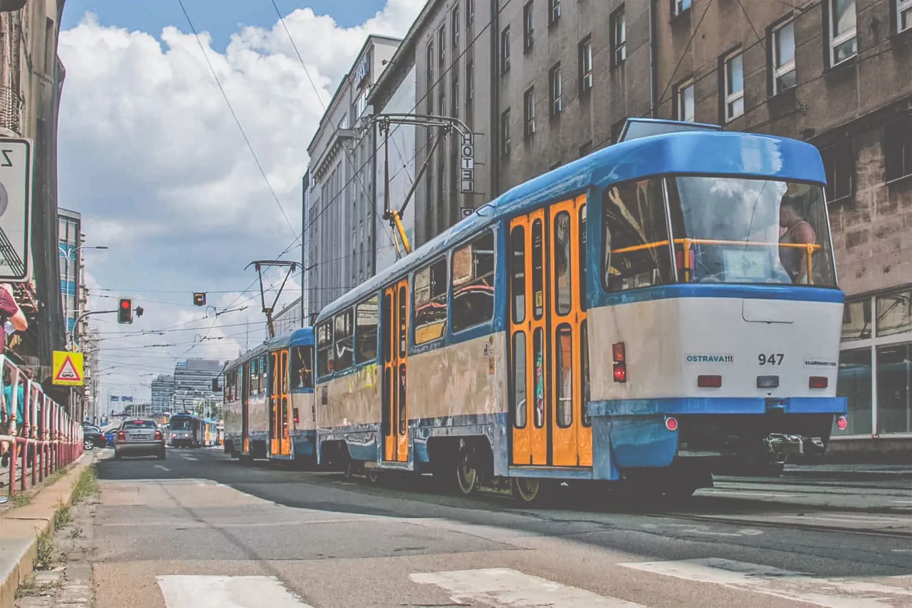 Blue yellow and white tram on a European road.