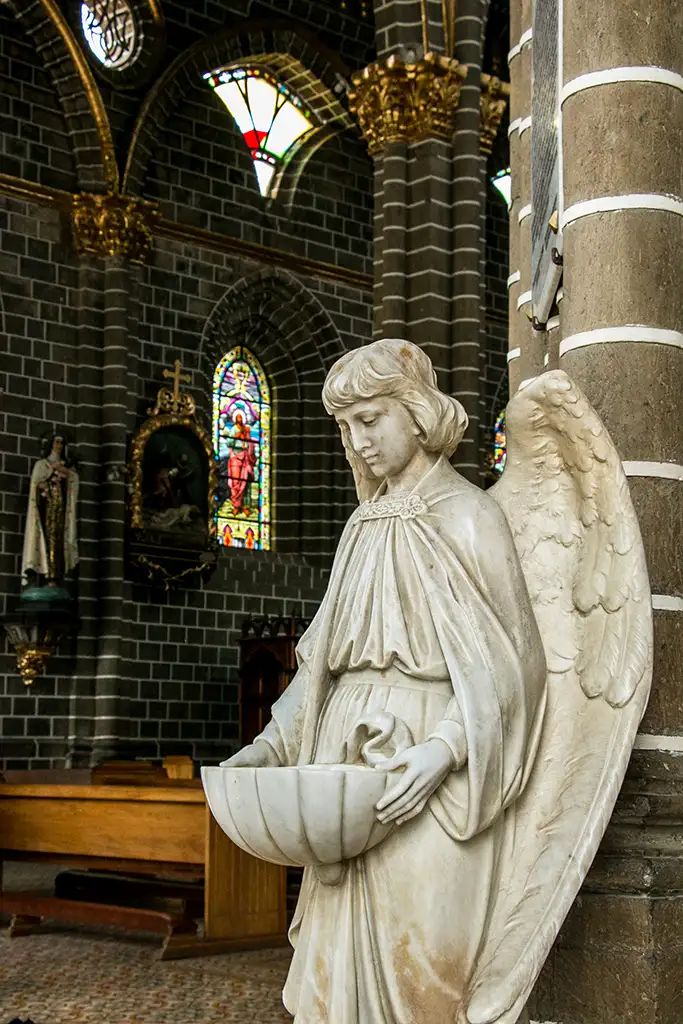 White statue of an angel, inside of a chuch.
