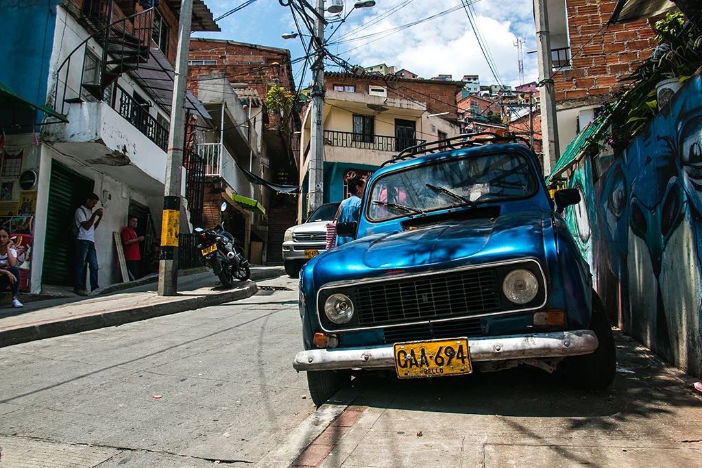 Blue car with yellow license plate on the side of the road